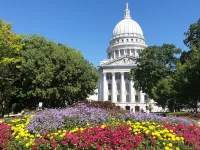 Na zdjęciu znajduje się Wisconsin State Capitol w otoczeniu kwiatów.