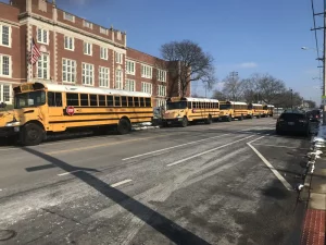 Zdjęcie autobusów szkolnych na tle szkoły.